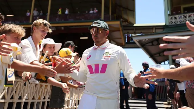 Usman Khawaja hi-fiving the crowd on his way onto the pitch