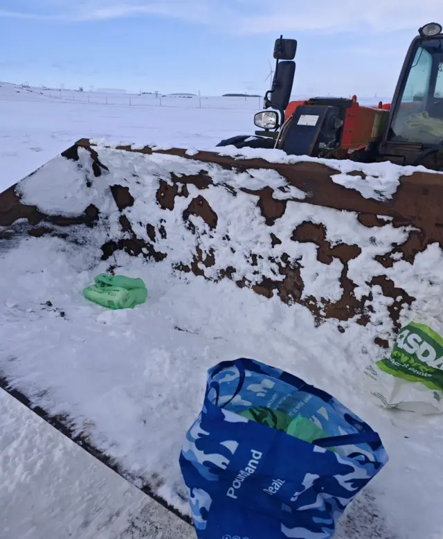 Food and supplies in the bucket of a farm vehicle being delivered to those in need