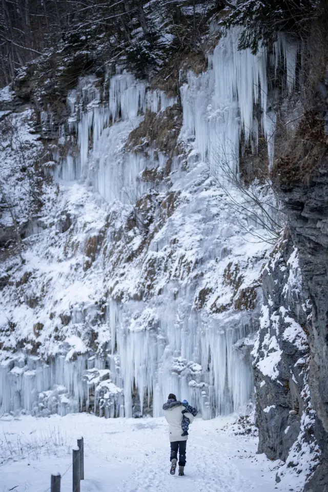A woman with her child walks on a snow-covered path next to icicles in Valens, Switzerland, 07 January 2026.