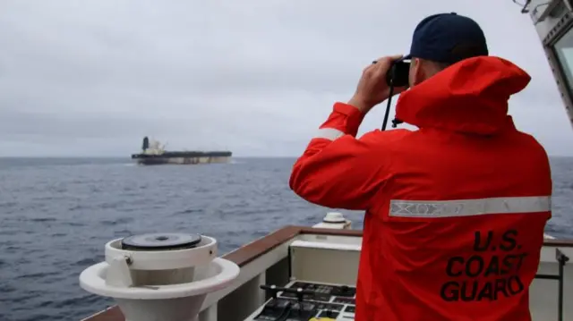 A US Coast Guard looking at Marinera thorough binoculars
