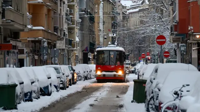 A bus travels on a road filled with snow-coated cars in Budapest, Hungary