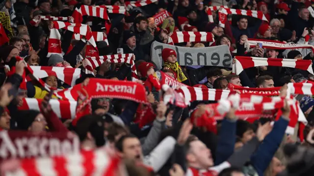Arsenal fans hold scarves up