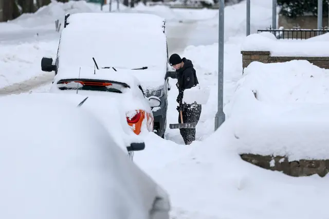 A man clears snow from a vehicle