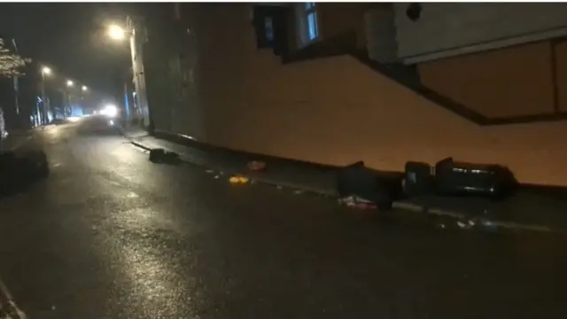 A Penzance street is empty, it is dark and wet and there are bins strewn around.