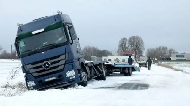 A lorry that has veered off the road into a snowy ditch in France