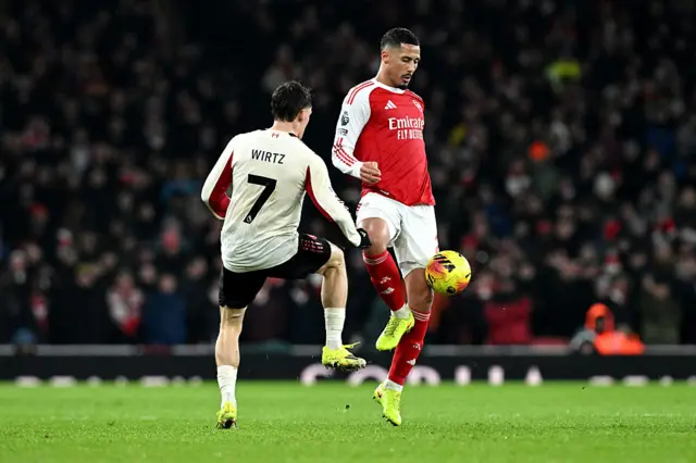 William Saliba of Arsenal passes the ball whilst under pressure from Florian Wirtz