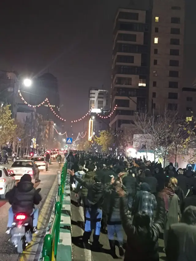 Crowds of protestors gather on a street in Tehran