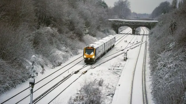 A train makes its way across snowy railway tracks