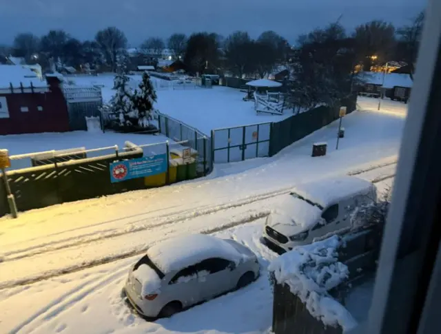 Thick snow covers a road and cars