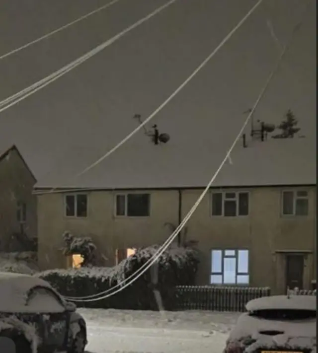 Cables drape low between houses on a snowy street