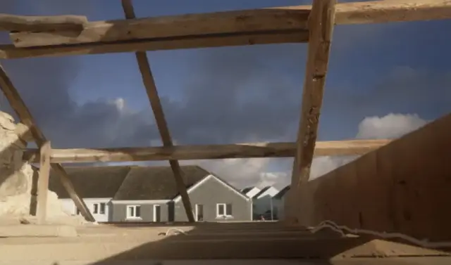 A picture taking from inside the property showing the damage of the roof from the inside looking out.