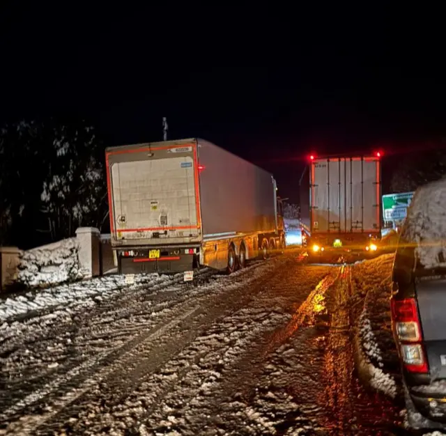 Two lorries side by side on a road covered in snow