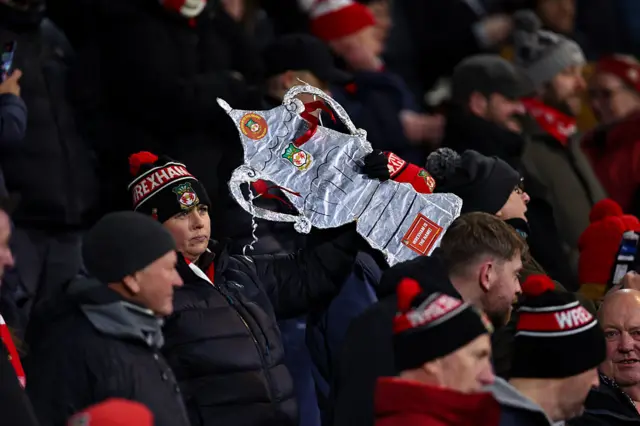 A fan of Wrexham holds up a replica tin foil FA Cup