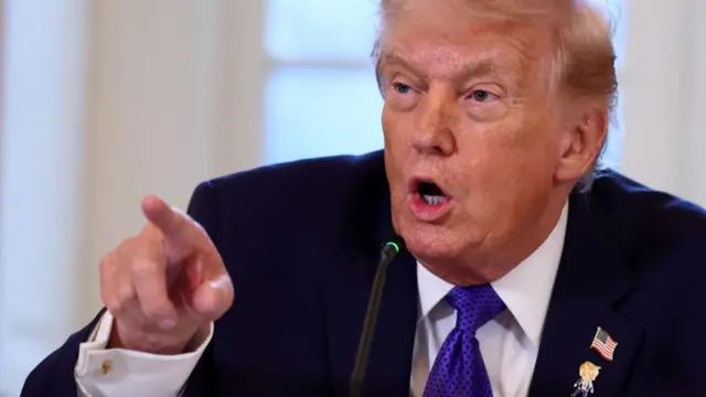 Donald Trump points at cameras during a q and a with reporters in the Oval Office