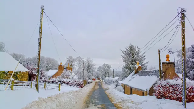 a traditional village with snow covering everywhere except for the road which is a little slushy