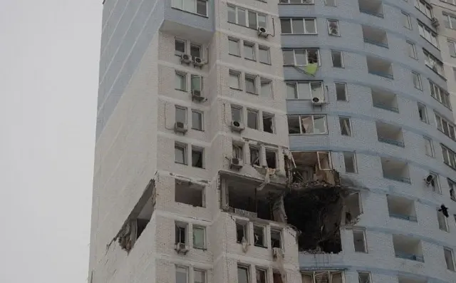 Close up of residential builidng in Kyiv with a large blackened hole in one of the apartments and substantial damage