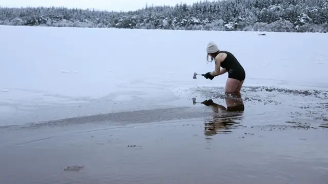 Ice swimmer Justina Pliuskeviciute uses an axe to break the ice on Loch Morlich, with Scotland in the grip of a deep freeze following Storm Goretti, near Aviemore, Scotland