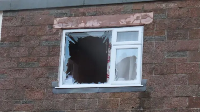 A smashed window in Guernsey, with shards of glass poking out from the frame.