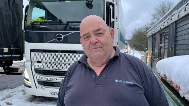A man in a polo shirt standing in front of a snowy truck