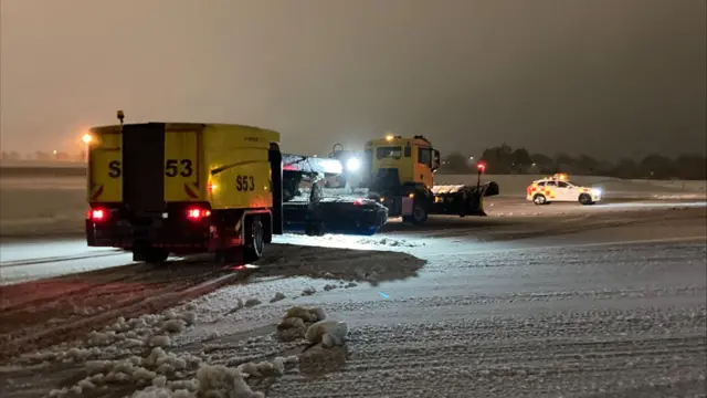 Vehicles work to remove the snow on the runway at an airport.