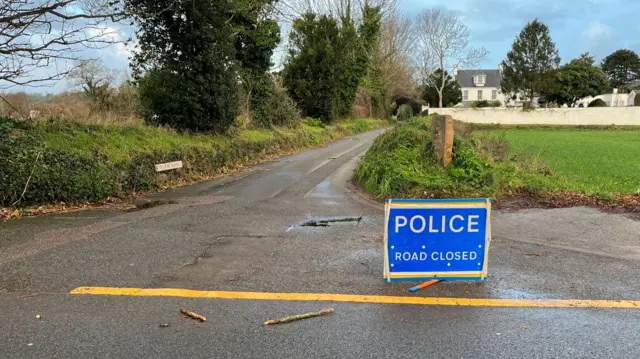 Police road closed sign at the junction of a road in Grouville, Jersey