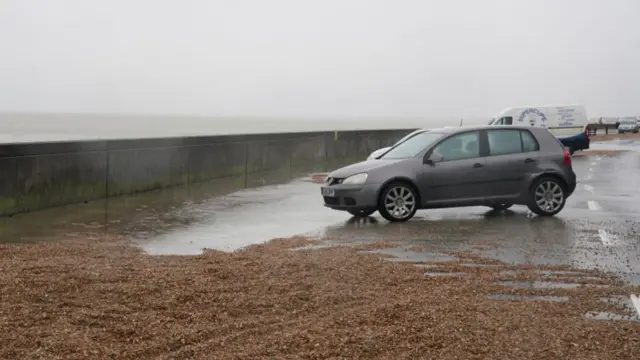A car drives through a puddle on the seafront