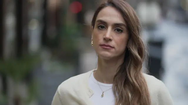 Mahsa Alimardani on London street, with long brown hair looking into the lens of the camera