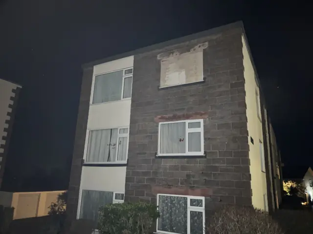A picture of a property that has been boarded up. There is a piece of wood on the top window.