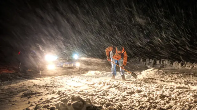 Man shoveling snow off road in Derbyshire