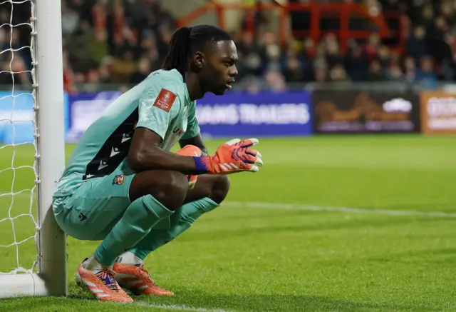 Okonkwo crouches down by his right post