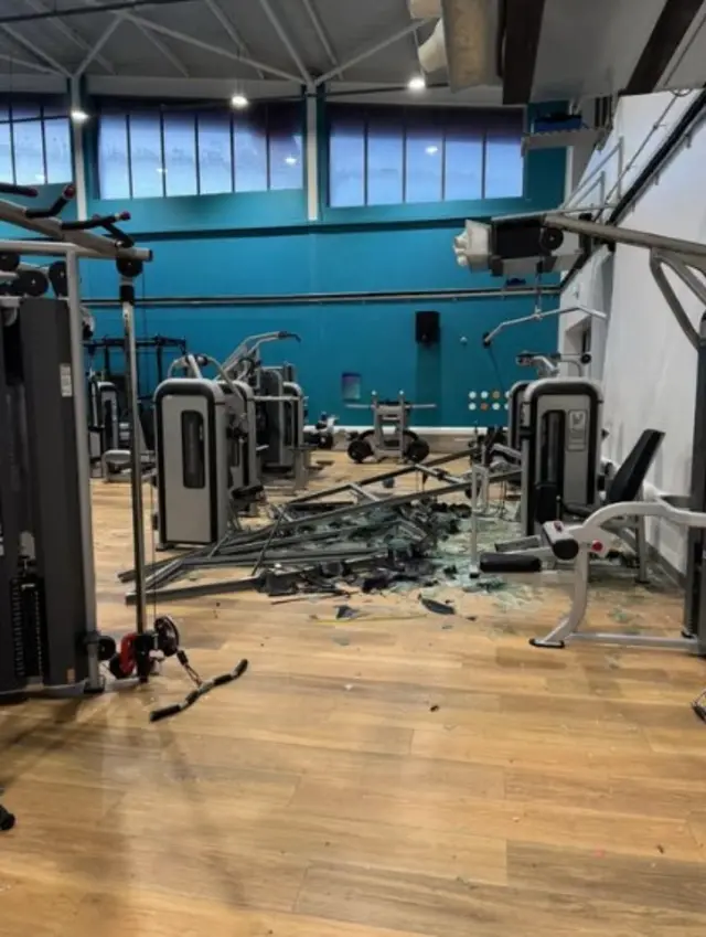 Damaged gym with smashed window and destroyed equipment
