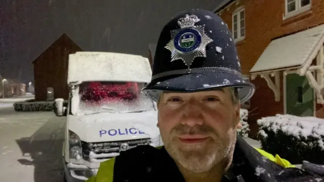 PC Anthony Allsopp in front of a snowy police van