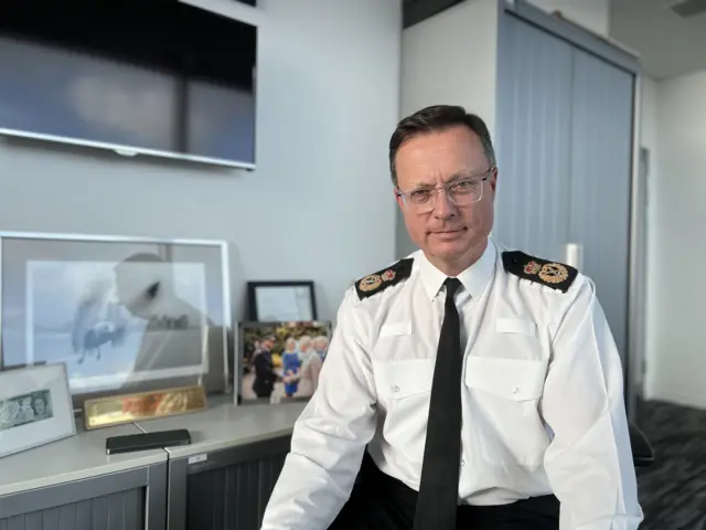 Robin Smith looking at the camera. He is wearing a white shirt and a black tie.