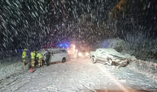 Firefighters surround one of two vehicles in the snow