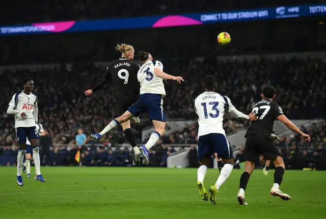 rling Haaland of Manchester City heads on target challenged by Radu Dragusin of Tottenham Hotspur