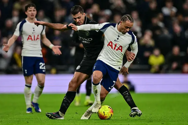 Manchester City's Spanish midfielder #16 Rodri (C) tackles Tottenham Hotspur's Dutch midfielder #07 Xavi Simons