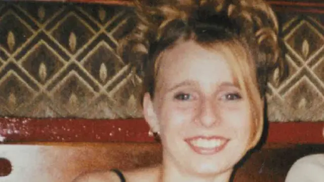 Victoria Hall is a white 17 year old blonde girl. In this picture, her hair is pinned up on her head, with one section framing the left hand side of her face. She is wearing a black vest top and smiling in what looks to be a bar or restaurant.