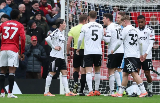 Fulham players remonstrate with referee John Brooks after Manchester United are awarded a penalty