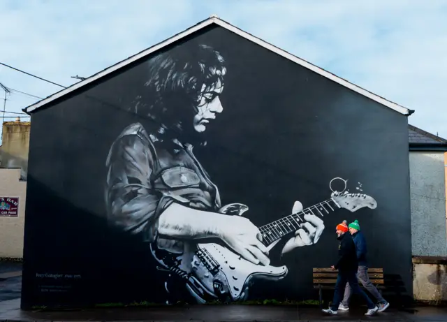 Fans arrive for the game past a Rory Gallagher mural