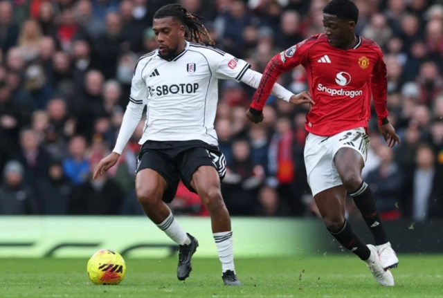 Fulham's Alex Iwobi in action with Manchester United's Kobbie Mainoo