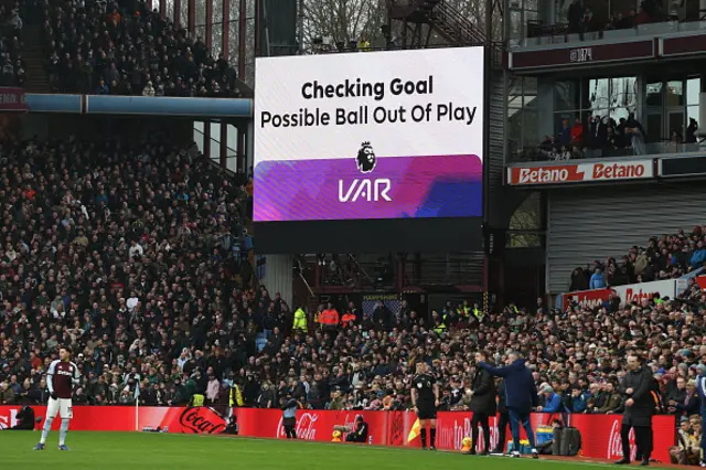 The big screen displays an ongoing VAR (Video Assistant Referee) review for a ball being out of play after Villa score