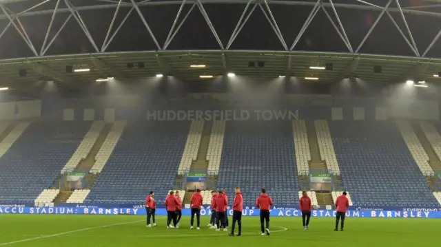 Doncaster players gather on the pitch in front one of the stands at ACCU StadiumHuddersfield's