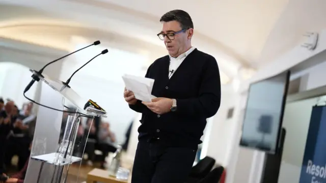 Andy Burnham addressing a Resolution Foundation event, holding papers at a lecturn