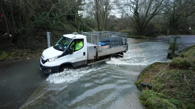 A van drives through a flooded road