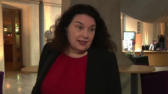 Katy Clark speaks to journalists as she stands in the reception area of a building