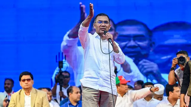Tarique Rahman gestures as he holds a microphone