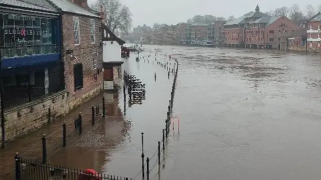 Murky brown water is flooding the seating area outside a pub