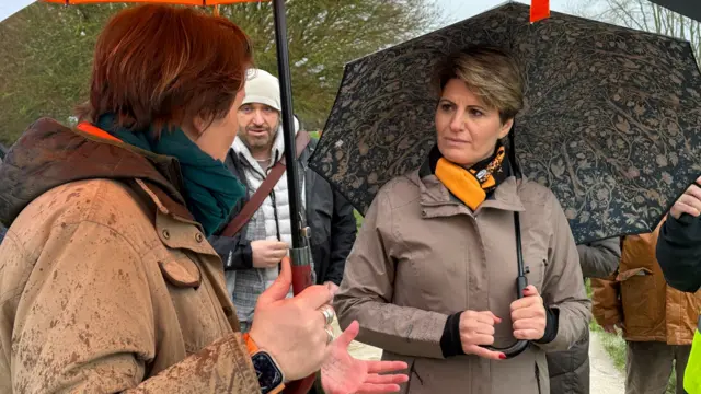 Flooding Minister Emma Hardy speaks to local under an umbrella