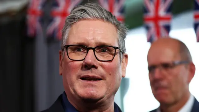Starmer appears in front of a banner of union jack flags