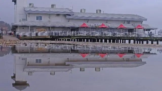 A beach pier is reflected perfectly in the water